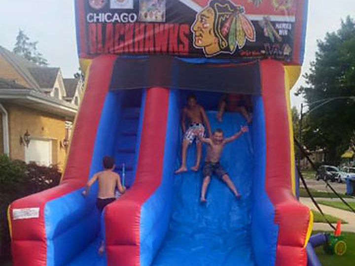 Inflatable water slide rental in a Chicago backyard with kids sliding